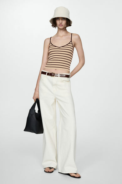 MANGO rokstrok met gestreepte bruine en beige kleuren, gedragen met een hoge taille witte broek, een hoed en een zwarte tas.
