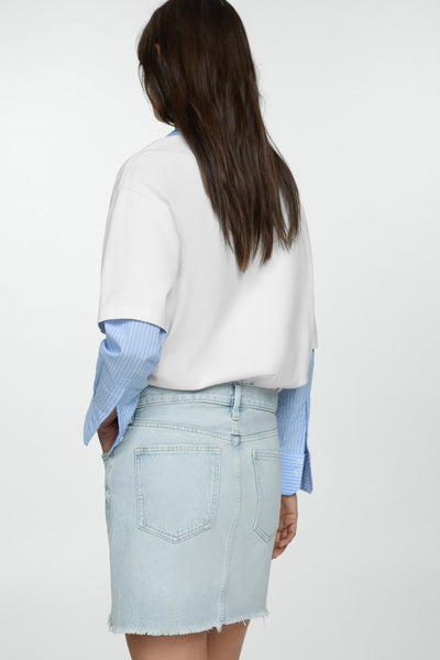 Mini-jupe en jean bleu moyen de MANGO, coupe droite, avec ourlet effiloché.