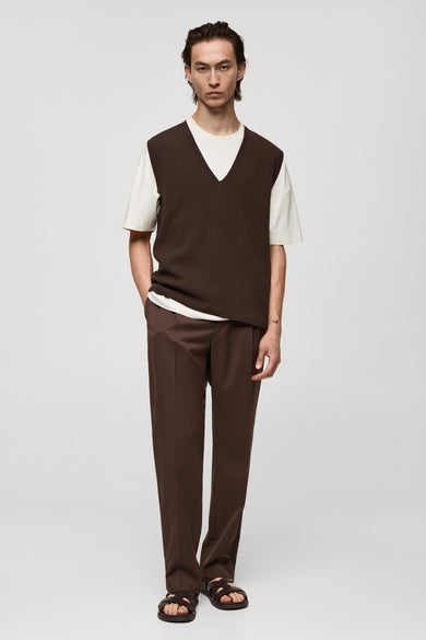 Débardeur marron van MANGO, porté sur un t-shirt blanc, avec un pantalon et des sandales assortis.