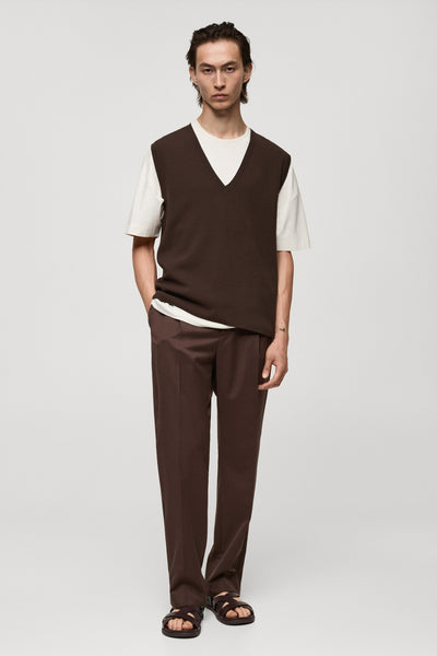 Débardeur marron van MANGO, porté sur un t-shirt blanc, avec un pantalon et des sandales assortis.