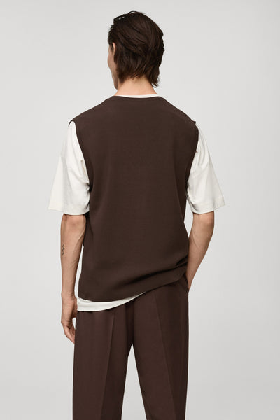 Débardeur marron by MANGO porté sur un t-shirt blanc, avec un pantalon assorti.