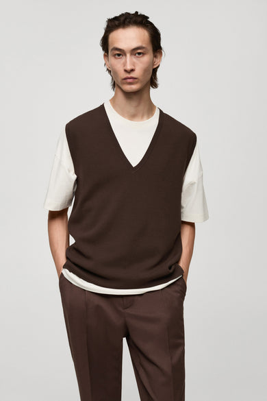 Débardeur brun by MANGO, porté sur un t-shirt blanc, avec un pantalon marron assorti.
