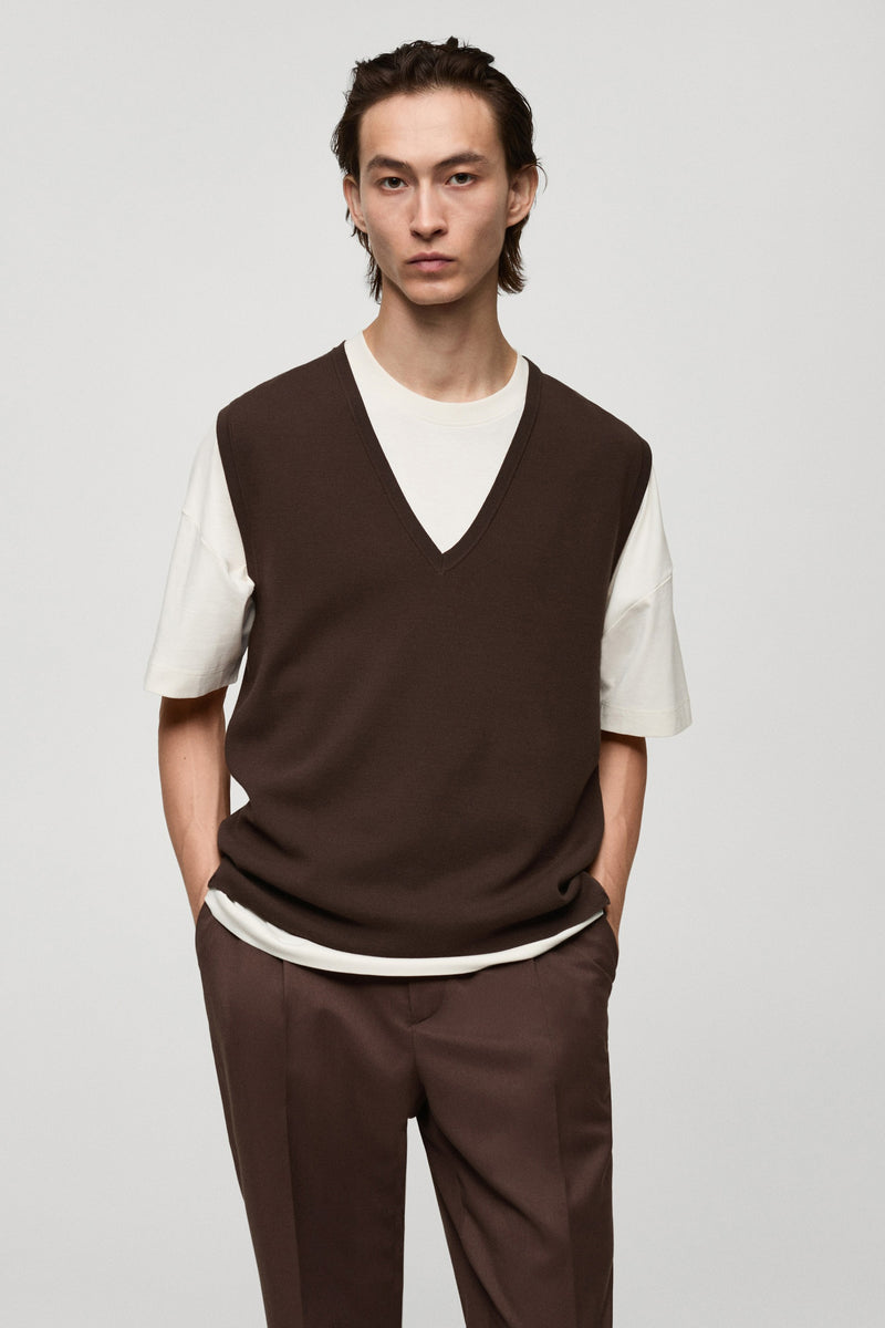Débardeur brun by MANGO, porté sur un t-shirt blanc, avec un pantalon marron assorti.