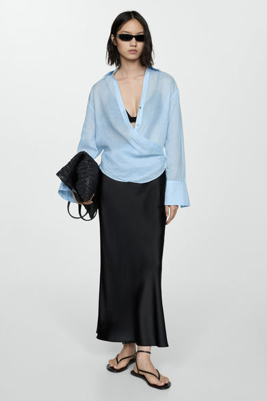 Zwarte satijnen lange rok van MANGO, gedragen met een blauw overhemd en sandalen met bandjes.