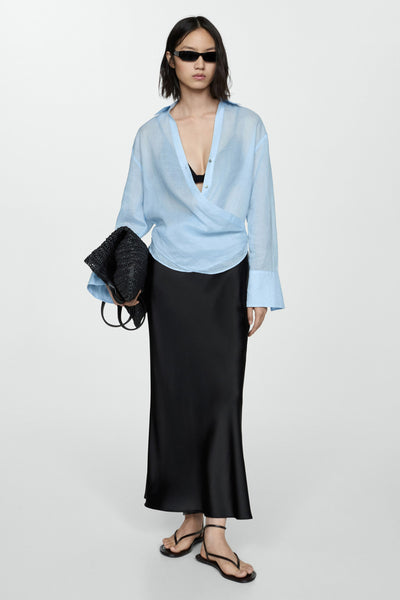 Zwarte satijnen lange rok van MANGO, gedragen met een blauw overhemd en sandalen met bandjes.