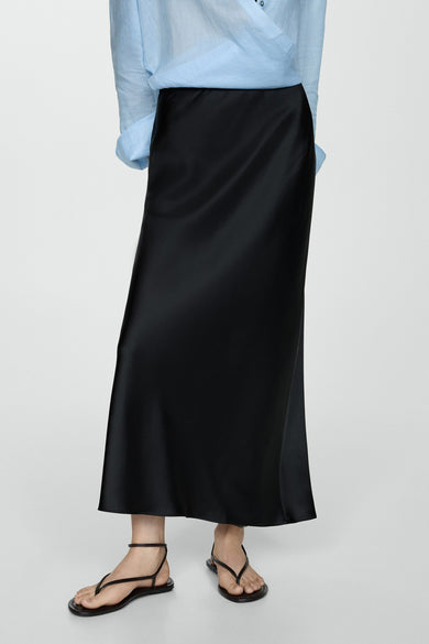 Zwarte lange satijnen rok van MANGO, gedragen met een blauw overhemd en minimalistische sandalen.