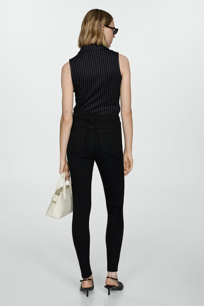 Zwarte skinny jeans van MANGO, gedragen met een gestreept topje en pumps met lage hak.