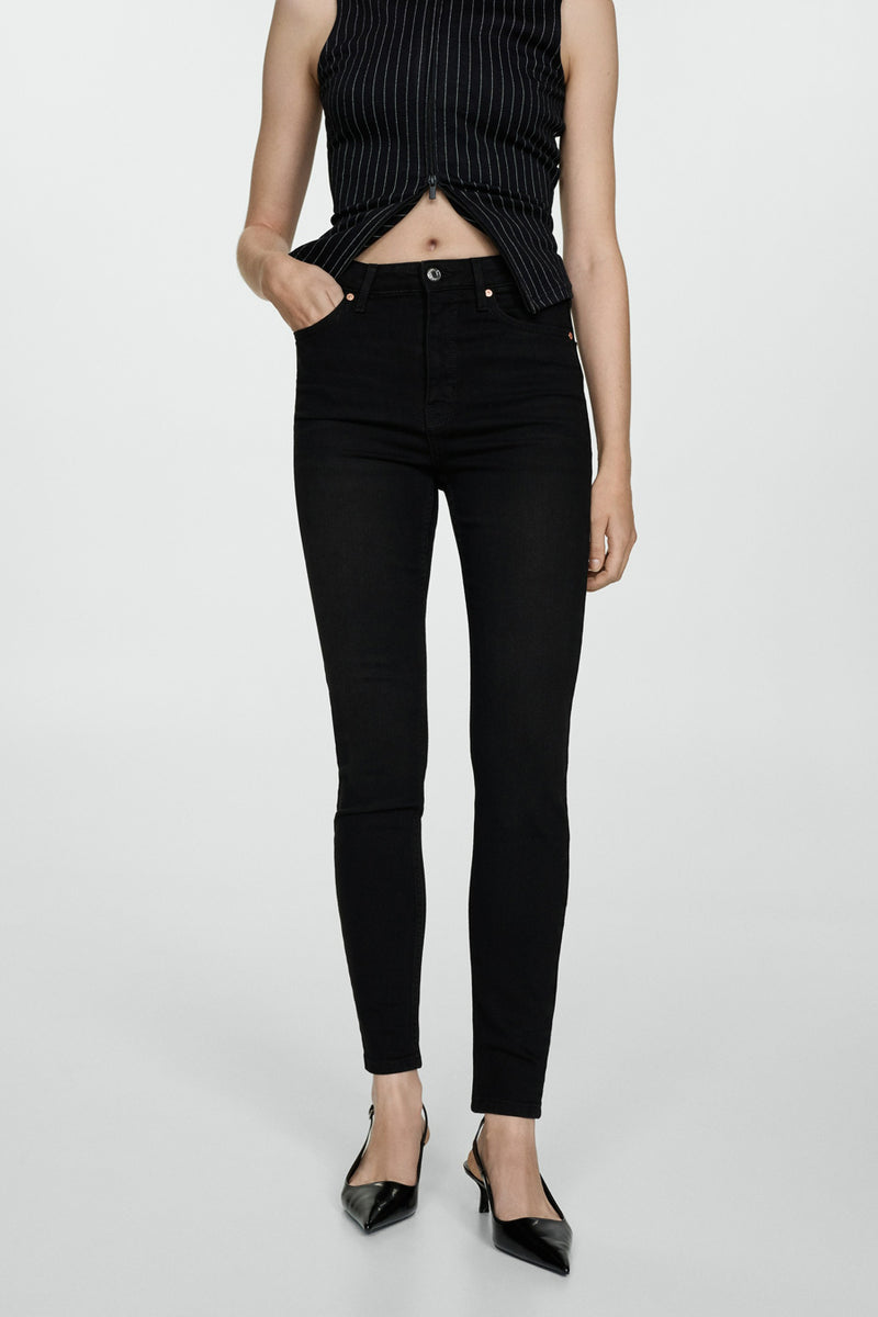 Zwarte skinny jeans van MANGO, gedragen met een gestreept topje en zwarte puntige pumps.