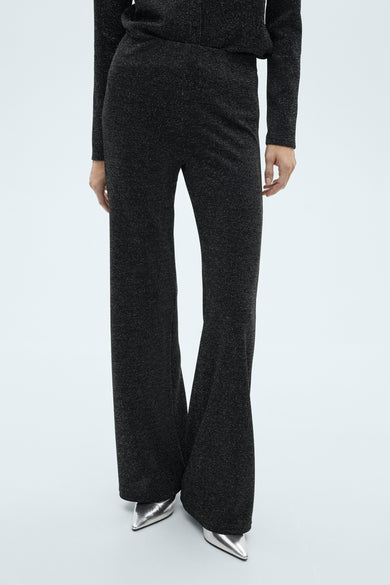 Grijze broek, van MANGO, met een uitlopende pasvorm en een glanzende textuur, gedragen met zilveren schoenen.