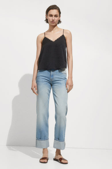 Zwarte mankelloze chemise van MANGO, met een randje van dentelle op de bovenkant, gedragen met een blauwe jeans.