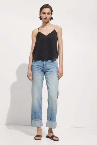Zwarte mankelloze chemise van MANGO, met een randje van dentelle op de bovenkant, gedragen met een blauwe jeans.