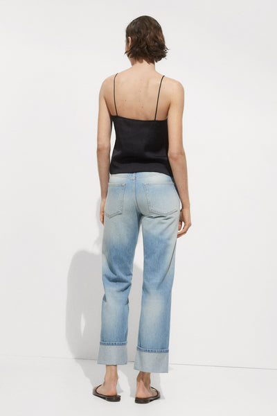 Zwarte mousseline blouse MANGO, dragen met een blauwe uitgebleekte jeans met opgerolde zoom en platte sandalen.