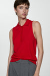 Rood MANGO poloshirt zonder mouwen, gedragen met een grijze fijne gestreepte broek en zilveren oorbellen.