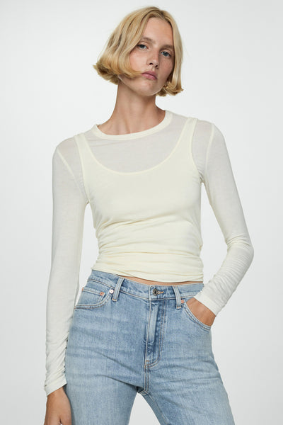 Slim jeans in licht denim van MANGO, gedragen met een beige top met lange mouwen.