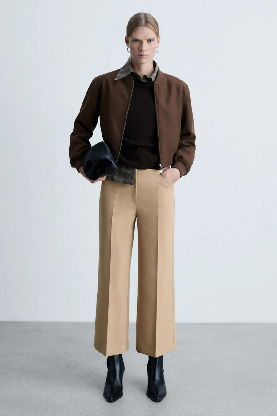 Beige broek van MANGO, rechte pasvorm, gedragen met zwarte enkellaarsjes en een bruin jack.