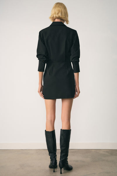 Robe noire à manches longues par MANGO, portée avec des bottes en cuir noires.