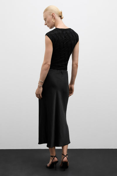 Chemisier à manches courtes multicolore de MANGO, avec motif texturé et porté avec une jupe noire mi-longue et des sandales à talons.
