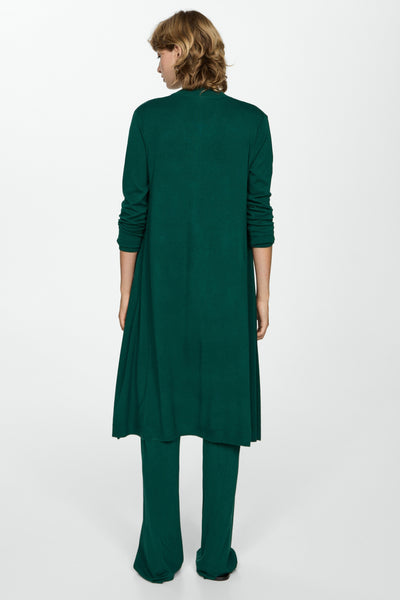Gilet vert de MANGO, style long avec manches longues, porté avec un pantalon assorti.

