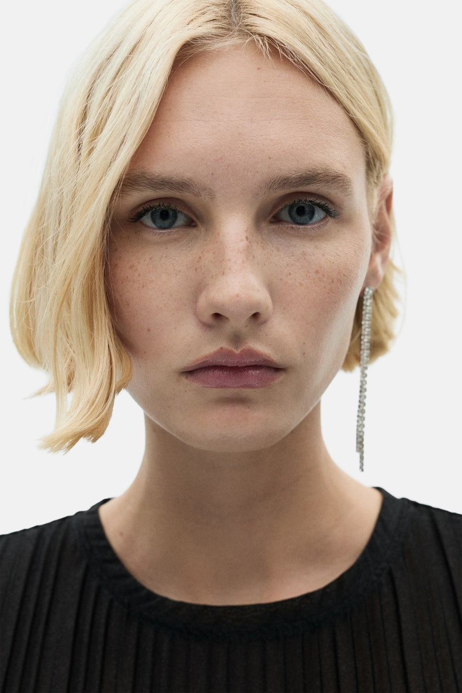 Robe à manches courtes multicolore de MANGO, portée avec une boucle d'oreille pendante, devant un fond blanc.
