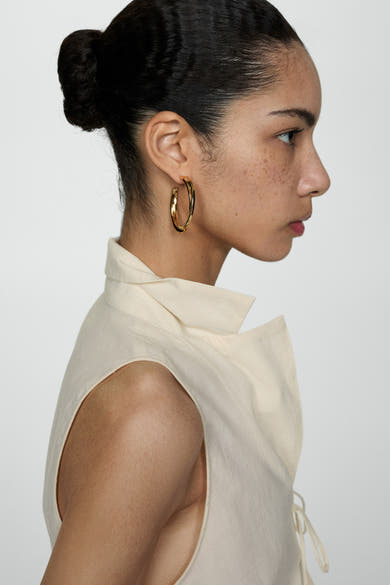 Blouse beige sans manches de MANGO, avec col structuré et détails noués.