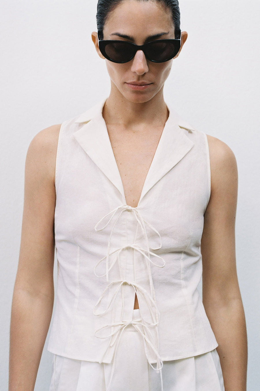 Chemisier beige sans manches de MANGO, avec col tailleur et laçage décoratif sur le devant.