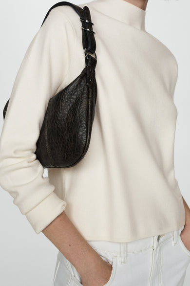 Pull à col rond blanc de MANGO, porté avec un sac à main texturé et un jean blanc.