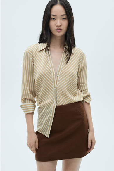 Korte bruine rok van MANGO, met een rechte pasvorm en zachte textuur, gedragen met een beige en witte gestreepte blouse.