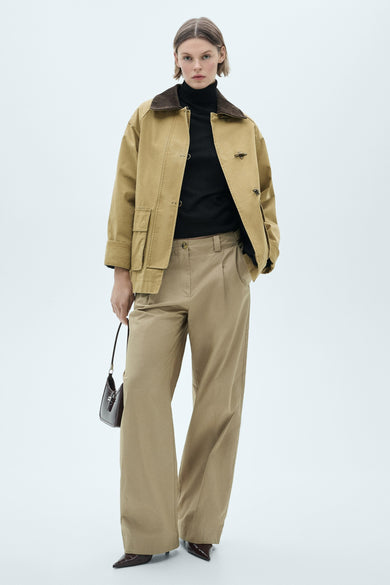 MANGO meerkleurige rolluikpullunder, gedragen met een hoge taille beige broek en een kaki jas met een bruine kraag.