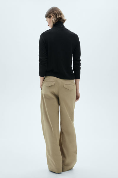 Zwarte rolletkragenpullover van MANGO, gedragen met een ruime beige broek.