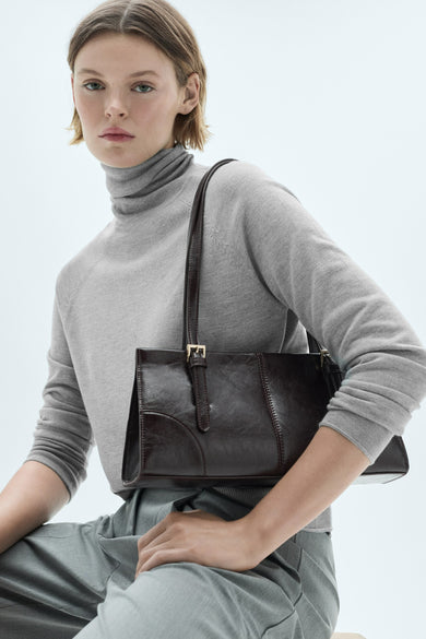 Beige coltrui van MANGO, gedragen met een grijze broek en een bruine leren handtas.