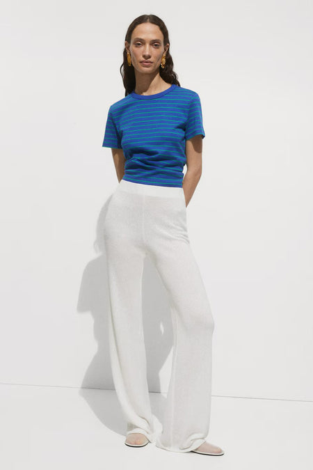 Blauwe stropdak met groene strepen van MANGO, gedragen met een witte broek met brede beenen.
