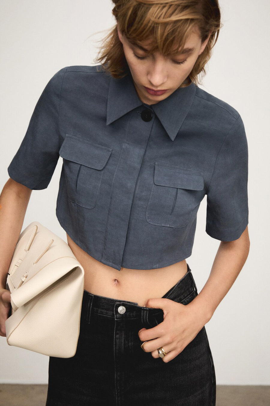Chemisier bleu à manches courtes de MANGO, avec deux poches à rabat, porté avec un jean noir.