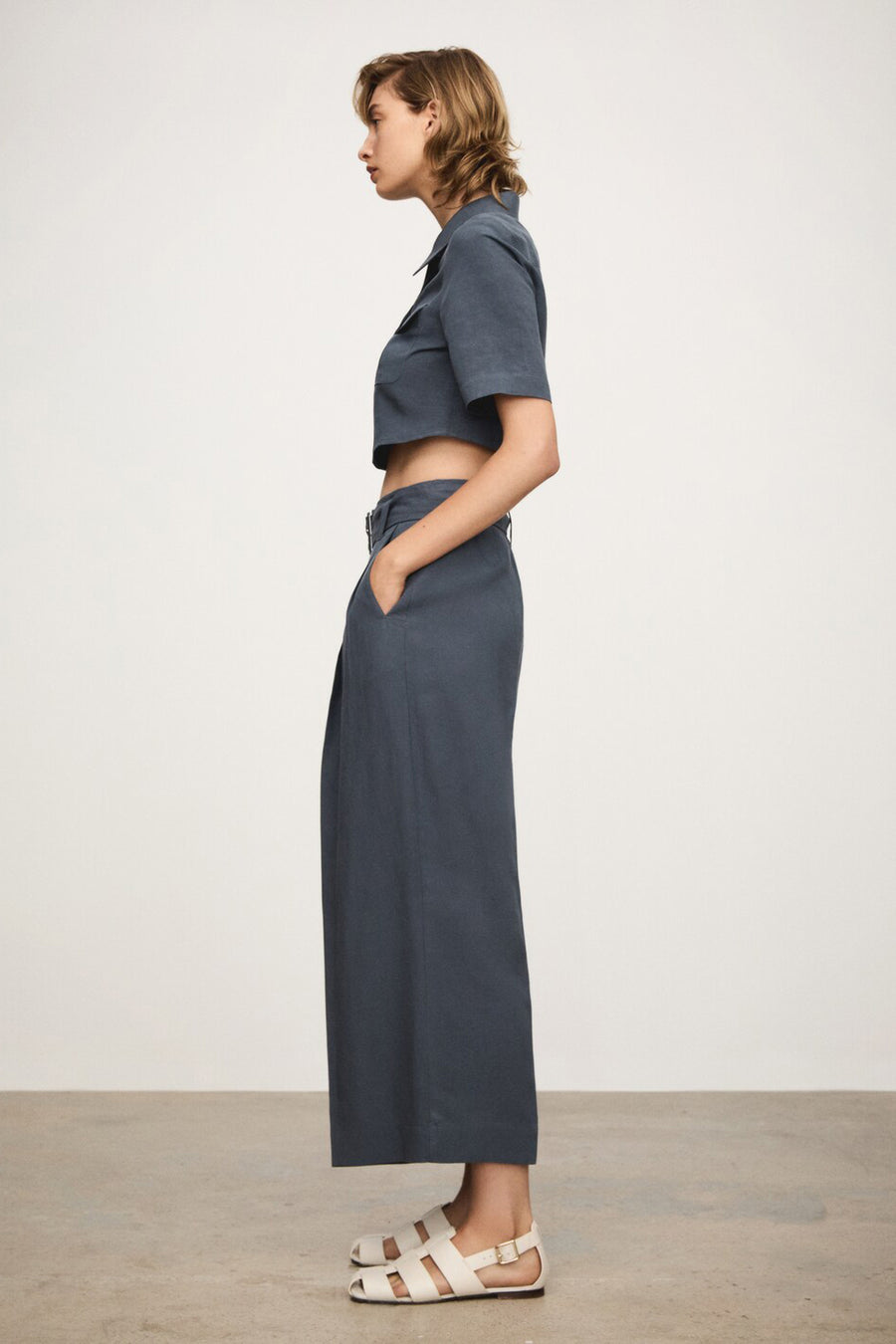 Chemisier bleu à manches courtes de MANGO, porté avec un pantalon taille haute et des sandales blanches.
