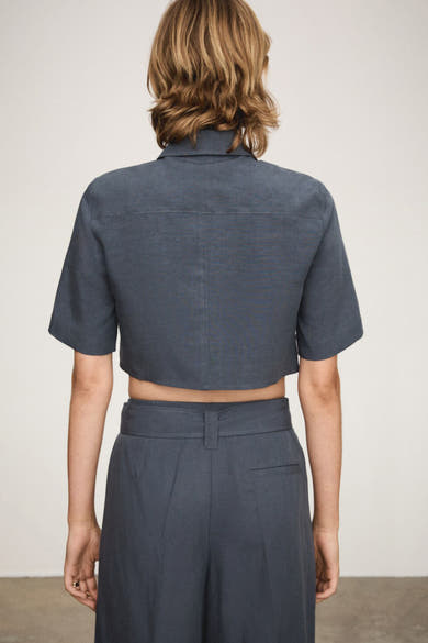 Chemise à manches courtes bleue de MANGO, vue de dos, avec pantalon assorti à taille haute.
