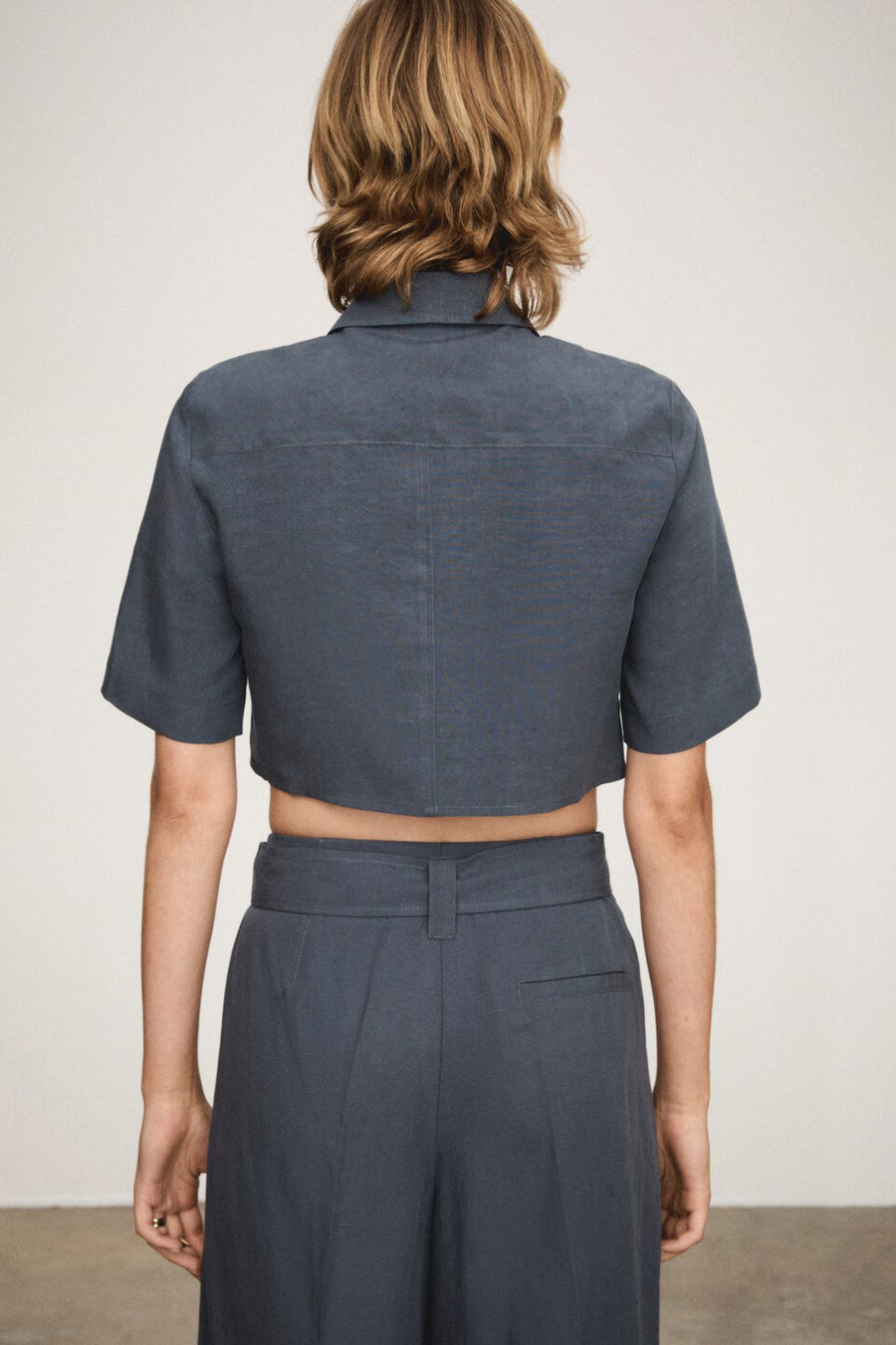 Chemise à manches courtes bleue de MANGO, vue de dos, avec pantalon assorti à taille haute.
