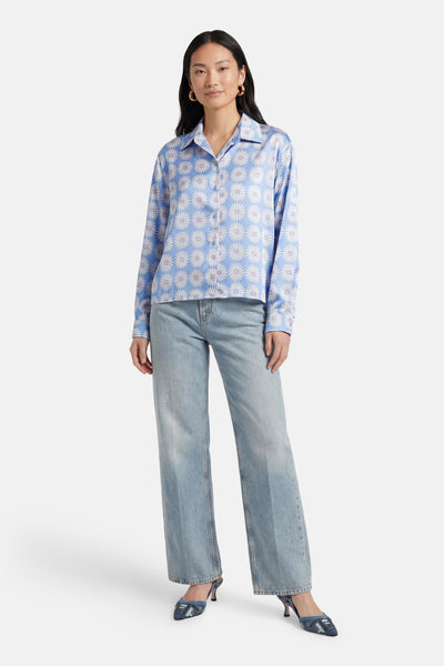 Chemise bleue à manches longues de Terra di Siena avec motif floral blanc, portée avec un jean décontracté.
