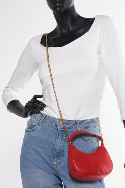 Rode schoudertas van Access®, gedragen met een high-waisted jeans en een wit T-shirt met lange mouwen.