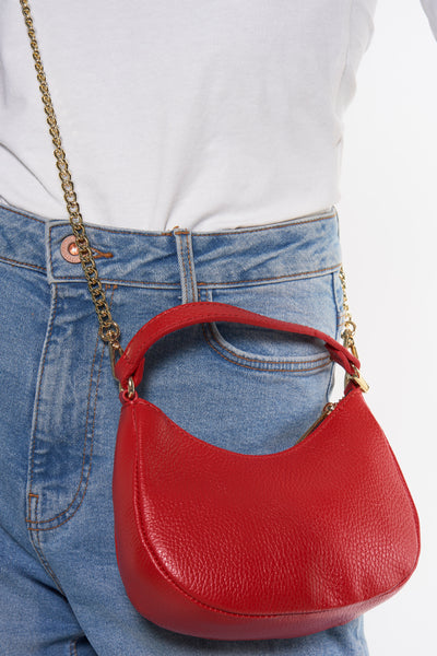 Rode leren schoudertas van Access® met gouden kettingriem, gedragen met een high-waisted jeans en een wit T-shirt.