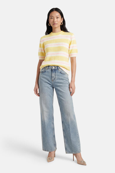Pull multicolore de Terra di Siena à rayures jaunes et roses, porté avec un jean taille haute et des escarpins décorés.