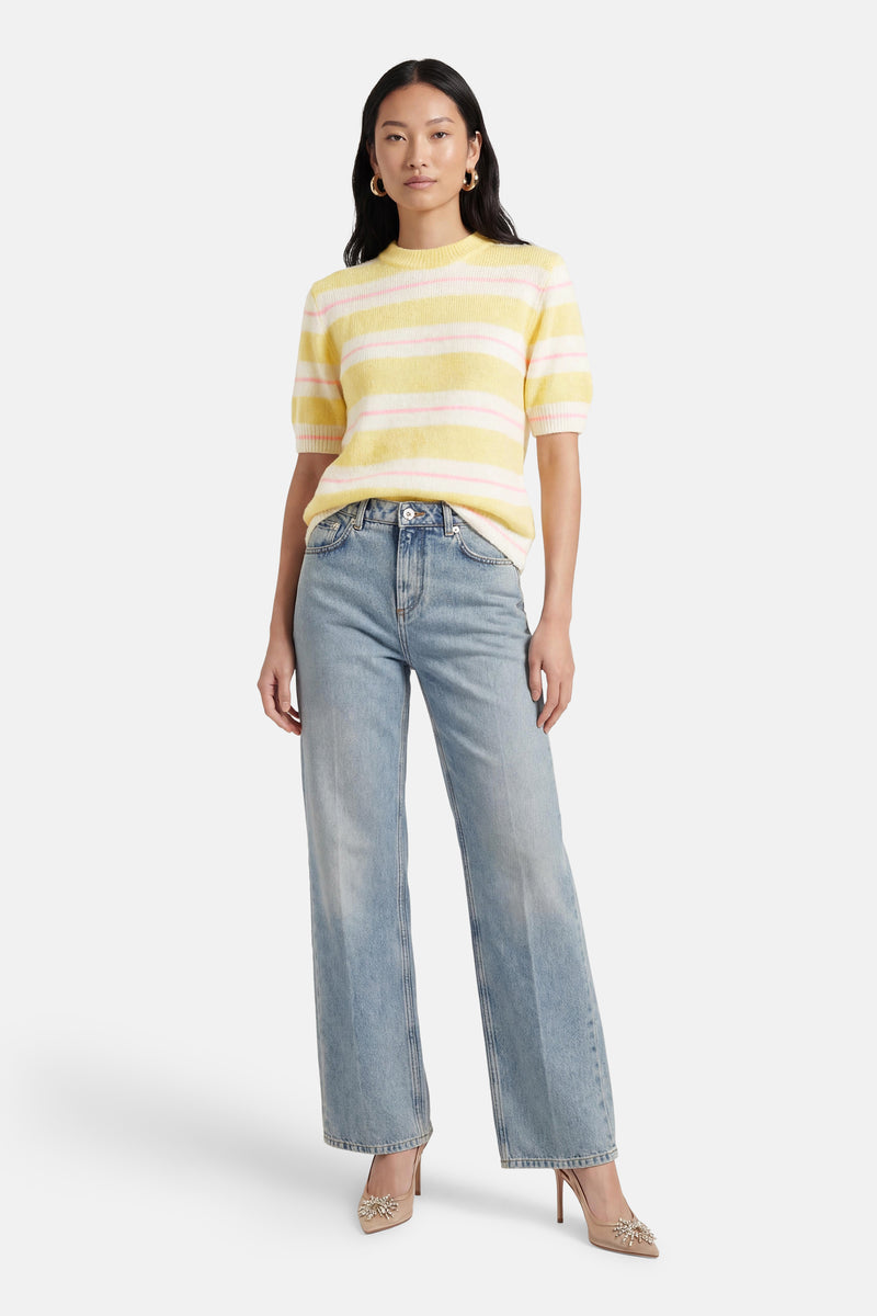 Pull multicolore de Terra di Siena à rayures jaunes et roses, porté avec un jean taille haute et des escarpins décorés.