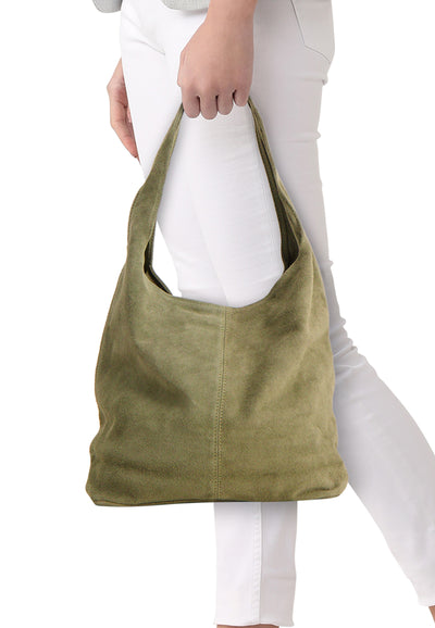Olive green suede shoulder bag with soft texture and front seam detail, worn by model in white pants, side view.