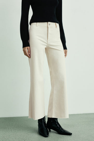 Wijde ecru denim jeans van MANGO, rechte pasvorm met rafelige zoom en zwarte enkellaarsjes.