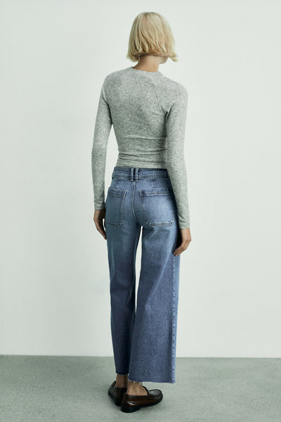 Wijde spijkerbroek in donkerblauw denim van Mango, gedragen met een grijze trui en bruine schoenen.