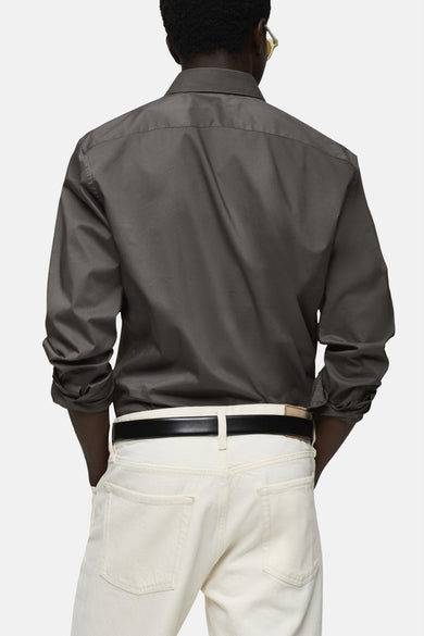 Chemise à manches longues grise de MANGO, vue de dos avec pantalon clair et ceinture noire.