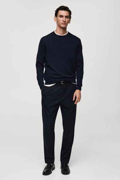 Ronde hals trui marineblauw van MANGO, gedragen met een wit T-shirt en een zwarte broek.