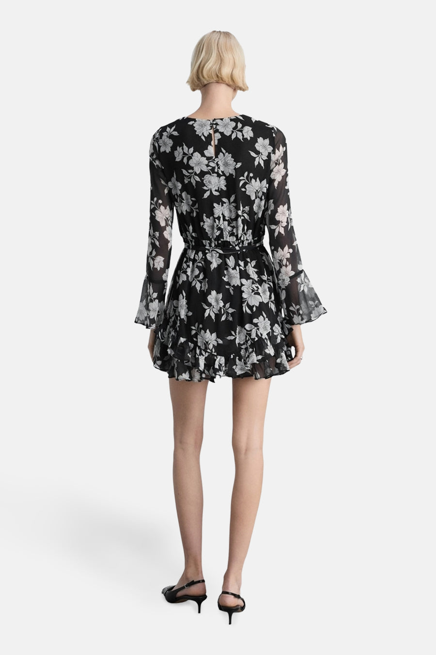Multikleurenjurk van MANGO, met zwart-wit bloemenpatroon, lange mouwen en een korte pasvorm.