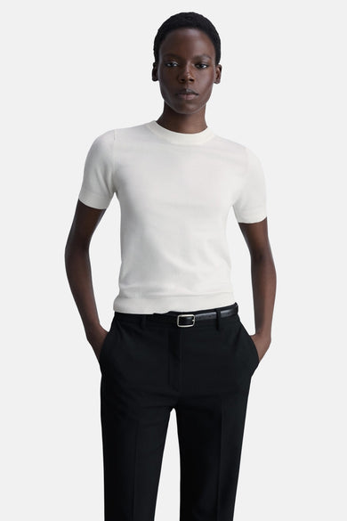 Witte ronde nekpull van MANGO, gedragen met een uitgestrekte zwarte broek.