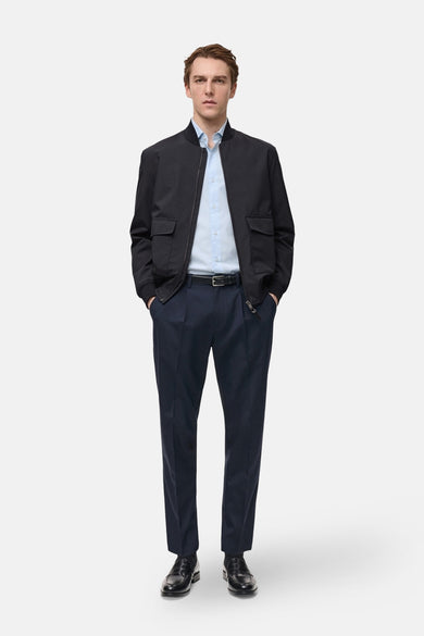 Chemise à manches longues bleue de MANGO, portée ouverte avec un blouson noir, un pantalon marine et des mocassins noirs.
