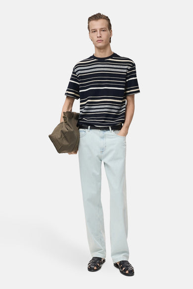 T-shirt à manches courtes bleu rayé de MANGO, porté avec un jean délavé et des sandales en cuir.