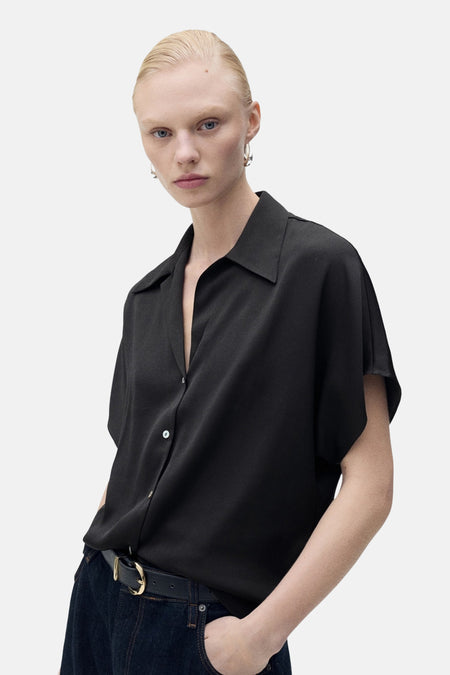 Zwart overhemd met korte mouwen van MANGO, gedragen met een wijde indigodenim, van achteren gezien.